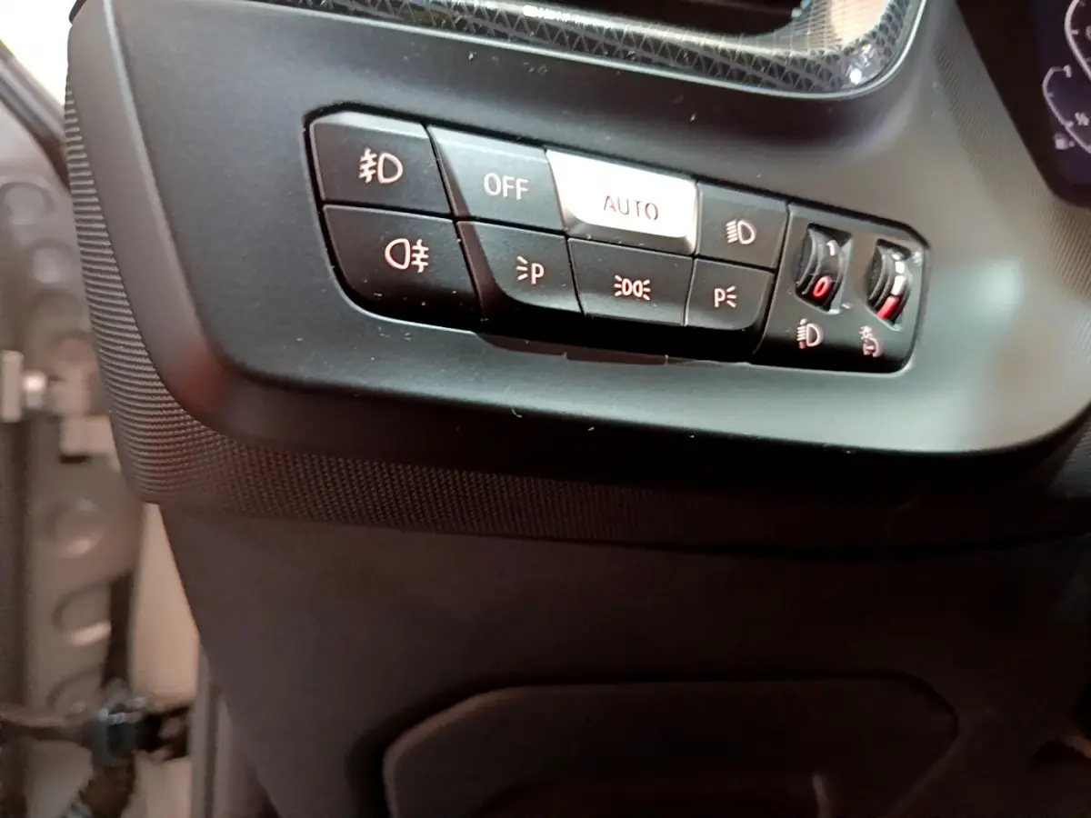 Gros plan sur les commandes d'éclairage à gauche du tableau de bord de la BMW Série 1 gris clair Edition Sport 2021.