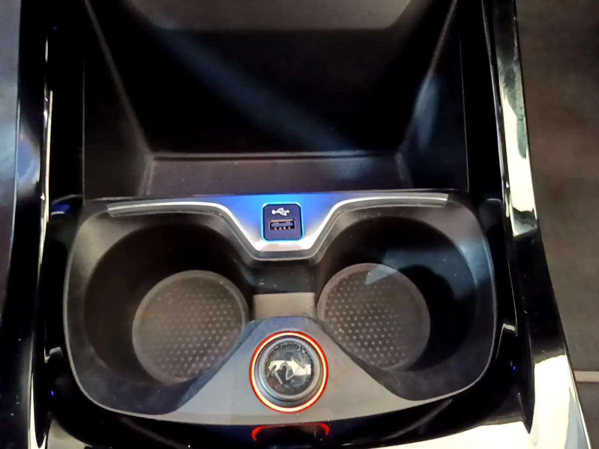 Gros plan sur la console centrale noire de la BMW Série 1 avec porte-gobelets et port USB visible.