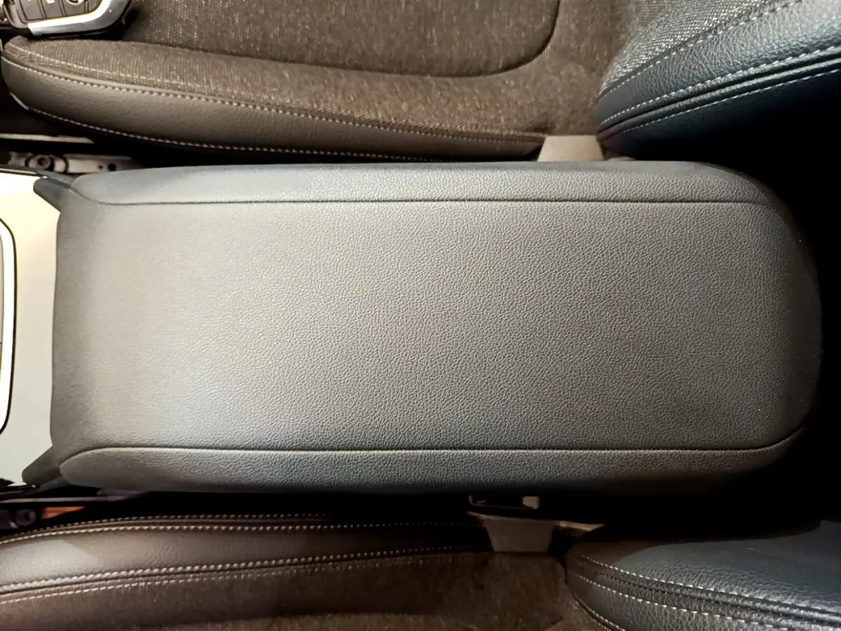 Gros plan sur l'accoudoir central en cuir noir entre les sièges avant d'une BMW Série 1 gris clair.