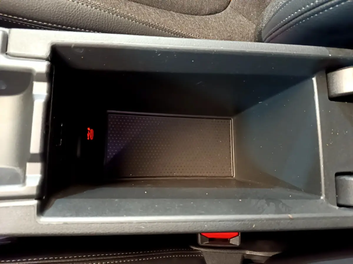 Gros plan sur le rangement central intérieur gris foncé de la BMW Série 1 Edition Sport avec témoin rouge allumé.