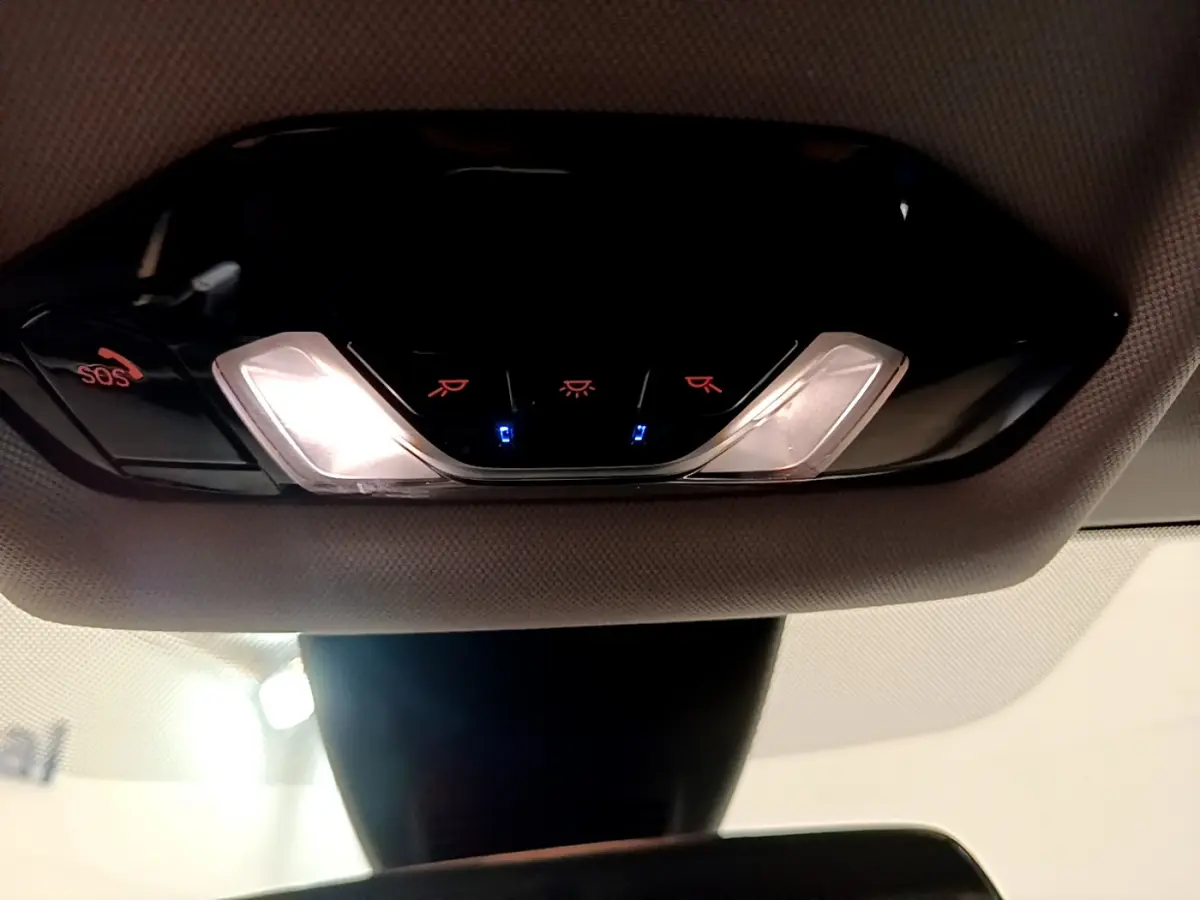 Plafonnier intérieur avec éclairage et bouton SOS de la BMW Série 1 gris clair, vue en contre-plongée depuis l'habitacle.