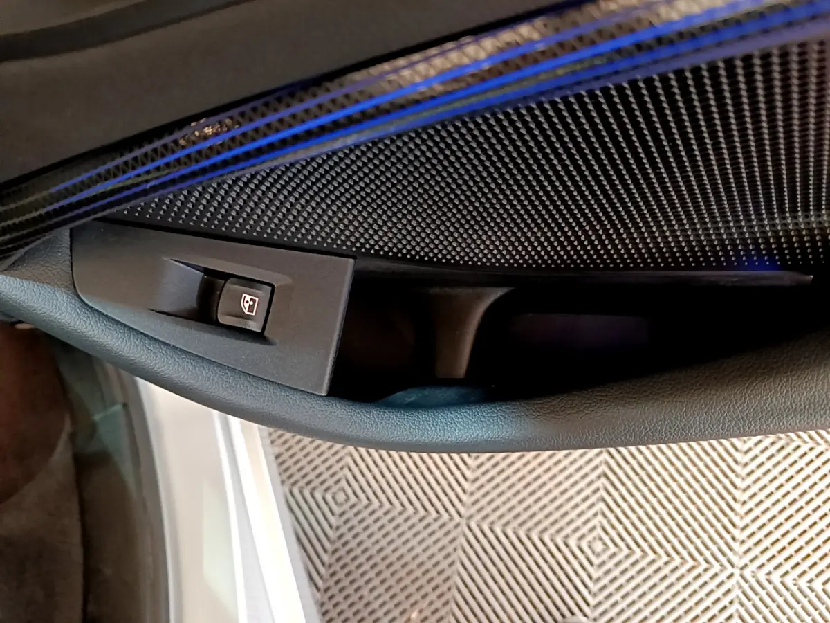 Gros plan sur la commande de lève-vitre côté gauche dans l'habitacle d'une BMW Série 1 gris clair Edition Sport 2021.