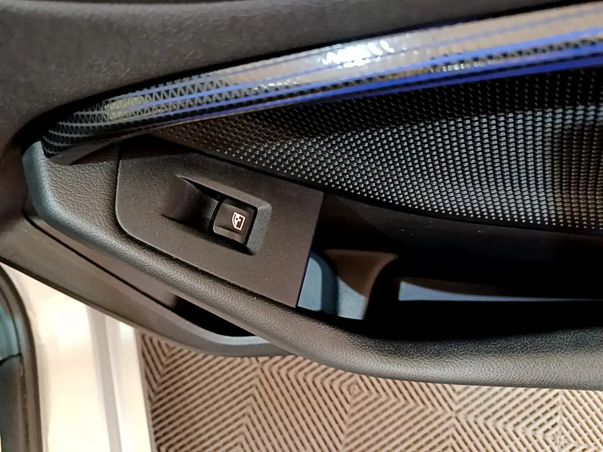 Gros plan sur le bouton de commande de la vitre côté conducteur dans une BMW Série 1 gris clair, intérieur noir.