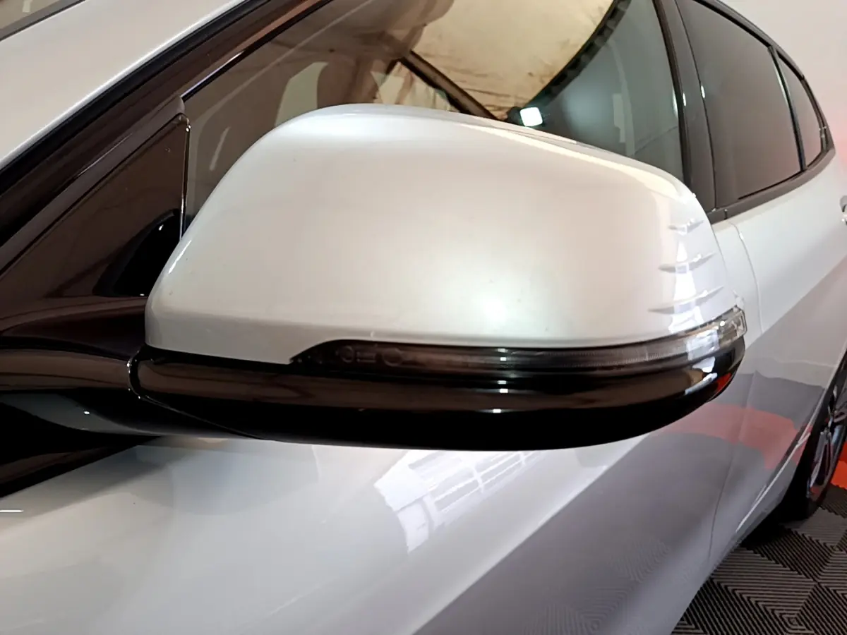 Gros plan sur le rétroviseur droit blanc avec clignotant intégré d'une BMW Série 1 gris clair Edition Sport 2021.