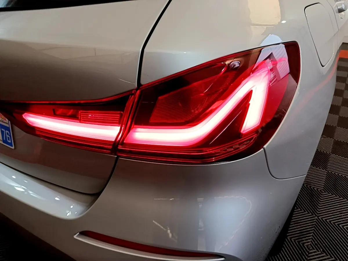 Gros plan sur le feu arrière droit allumé d'une BMW Série 1 gris clair, version Edition Sport 2021.