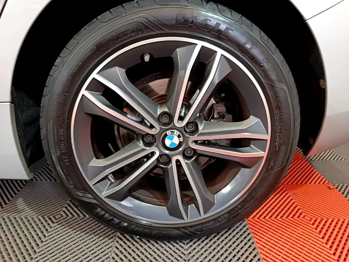 Gros plan sur la jante alliage gris foncé et le pneu Goodyear d’une BMW Série 1 gris clair, côté avant droit.