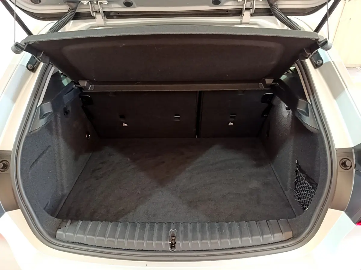 Coffre ouvert vu de l'arrière d'une BMW Série 1 gris clair, montrant l'espace de chargement vide et la tablette de séparation.