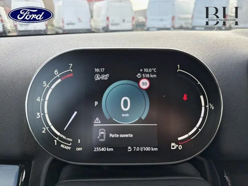 Tableau de bord numérique de MINI Countryman Cooper 2023, affichage vitesse et alertes, vue frontale rapprochée.