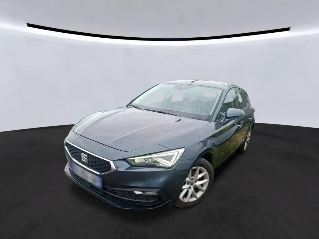 SEAT Leon gris vue 3/4 avant droit, mettant en valeur les phares LED et la calandre hexagonale distinctive.