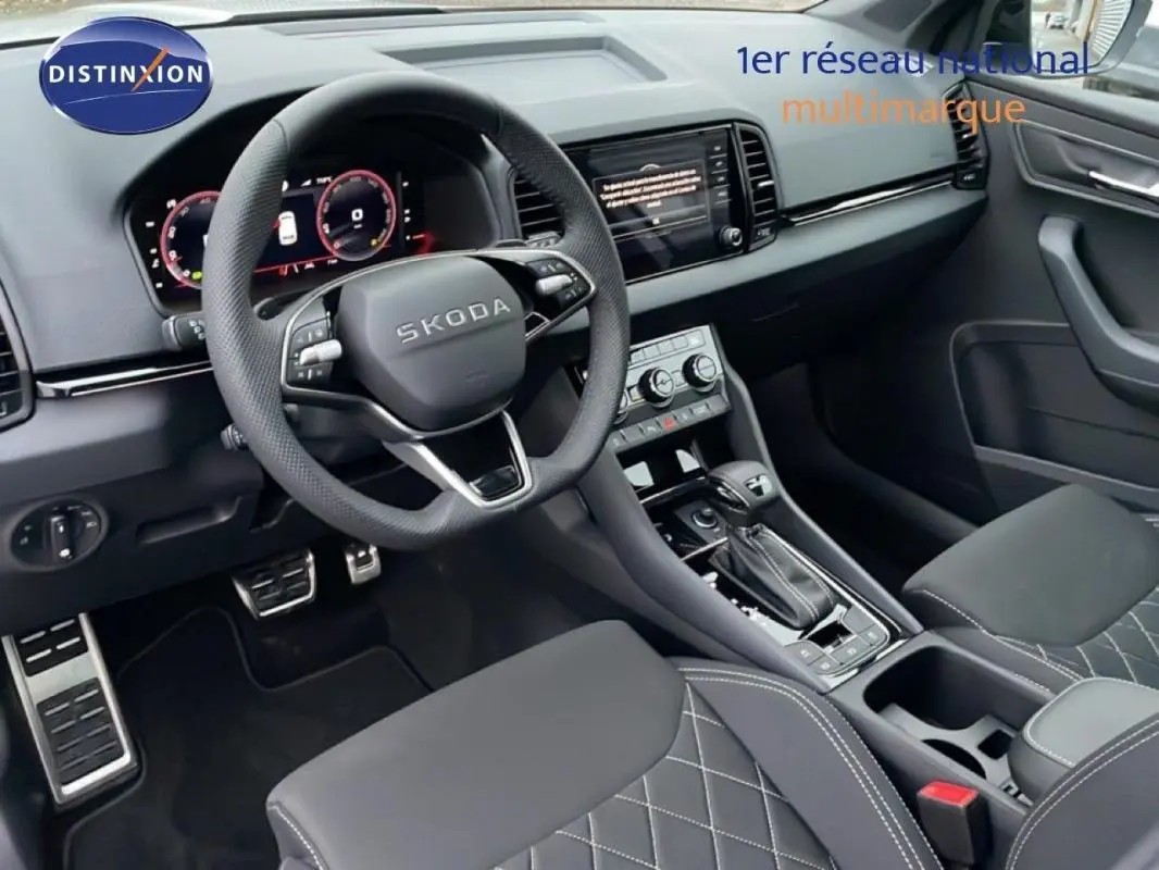 Vue intérieure avant du Skoda Karoq 2025, volant cuir multifonctions, console centrale avec écran tactile et sièges noirs matelassés.