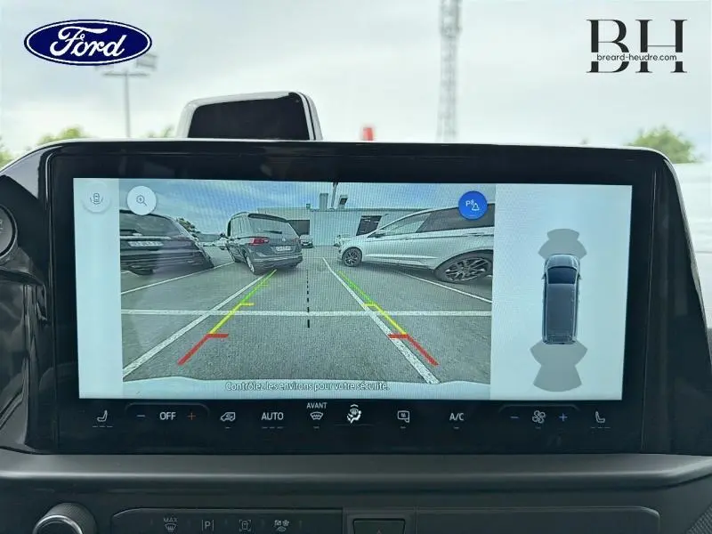 Écran tactile du Ford Transit Custom hybride montrant la caméra de recul avec lignes de guidage en parking extérieur.
