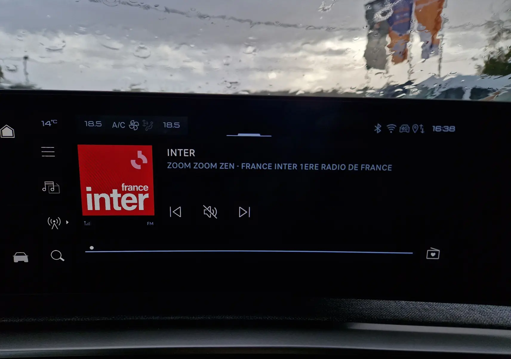 Écran tactile panoramique 21 pouces du Peugeot 3008 gris Artense, affichant la radio France Inter sous pluie.
