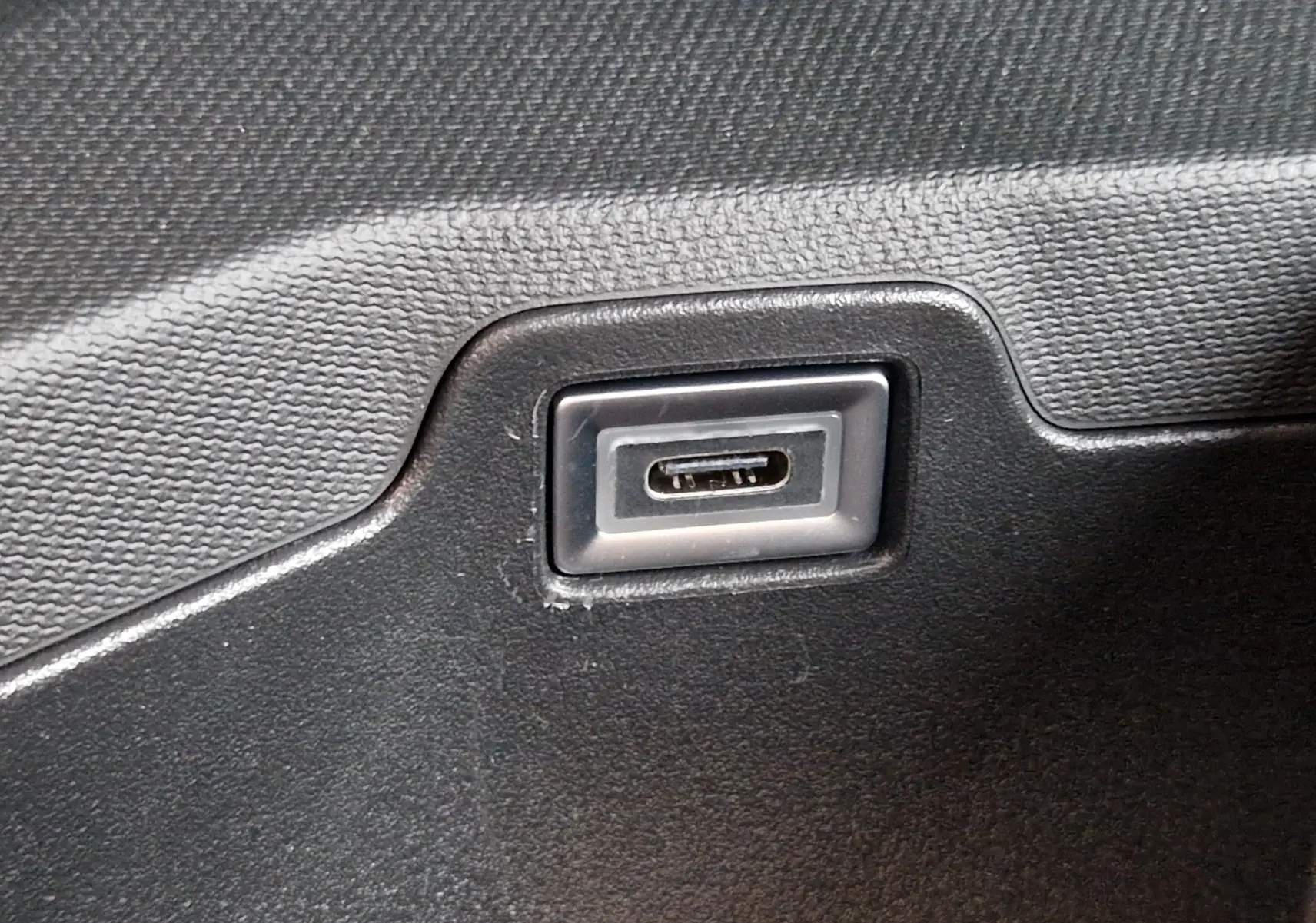 Gros plan sur un port USB-C intégré dans la garniture intérieure noire d'un Peugeot 3008 Gris Artense 2025.