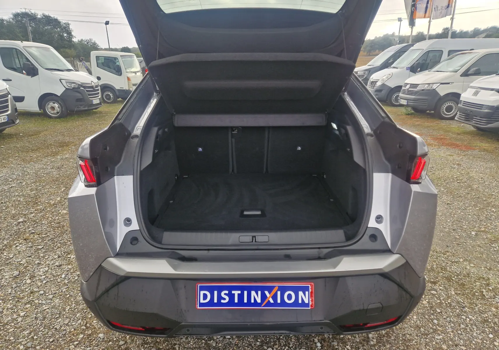 Vue arrière du Peugeot 3008 gris Artense avec coffre ouvert, montrant l'espace de chargement vide et les feux arrière allumés.