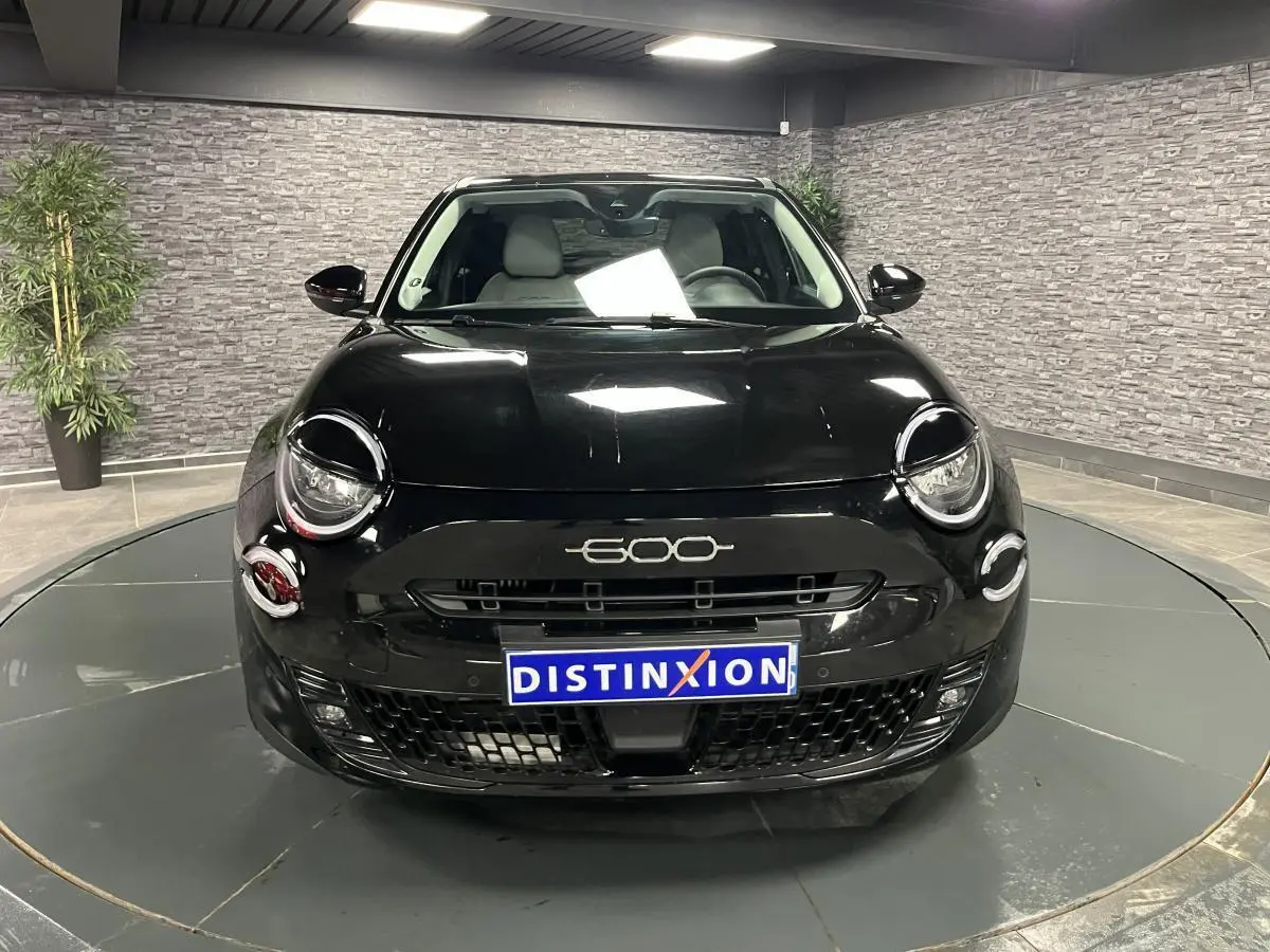 Vue frontale d'une FIAT 600 noire 2024 avec logo 600 chromé et calandre noire brillante en intérieur showroom.