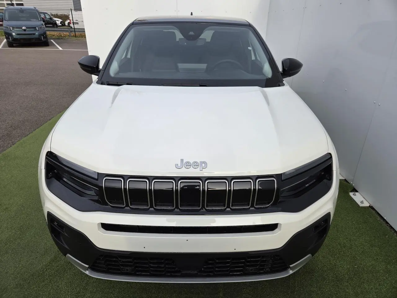 Vue avant d'un Jeep Avenger 2025 blanc Snow avec calandre gloss black et toit Volcano noir.