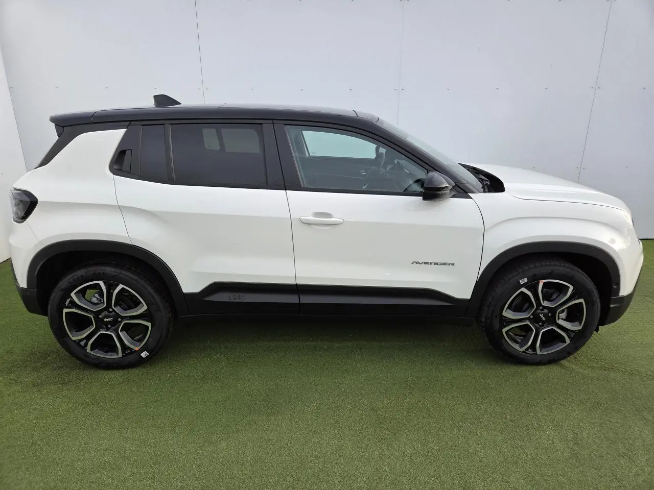 Profil côté gauche du Jeep Avenger 2025 blanc Snow avec toit noir Volcano et jantes alliage 18 pouces.