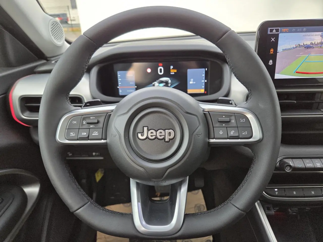 Volant Jeep noir avec commandes intégrées, tableau de bord numérique et écran tactile affichant la caméra de recul.