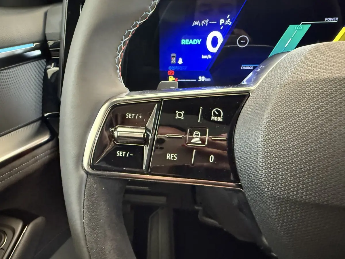 Gros plan sur le volant cuir noir et les commandes de régulateur de vitesse du Renault Espace gris foncé 2025 esprit Alpine.