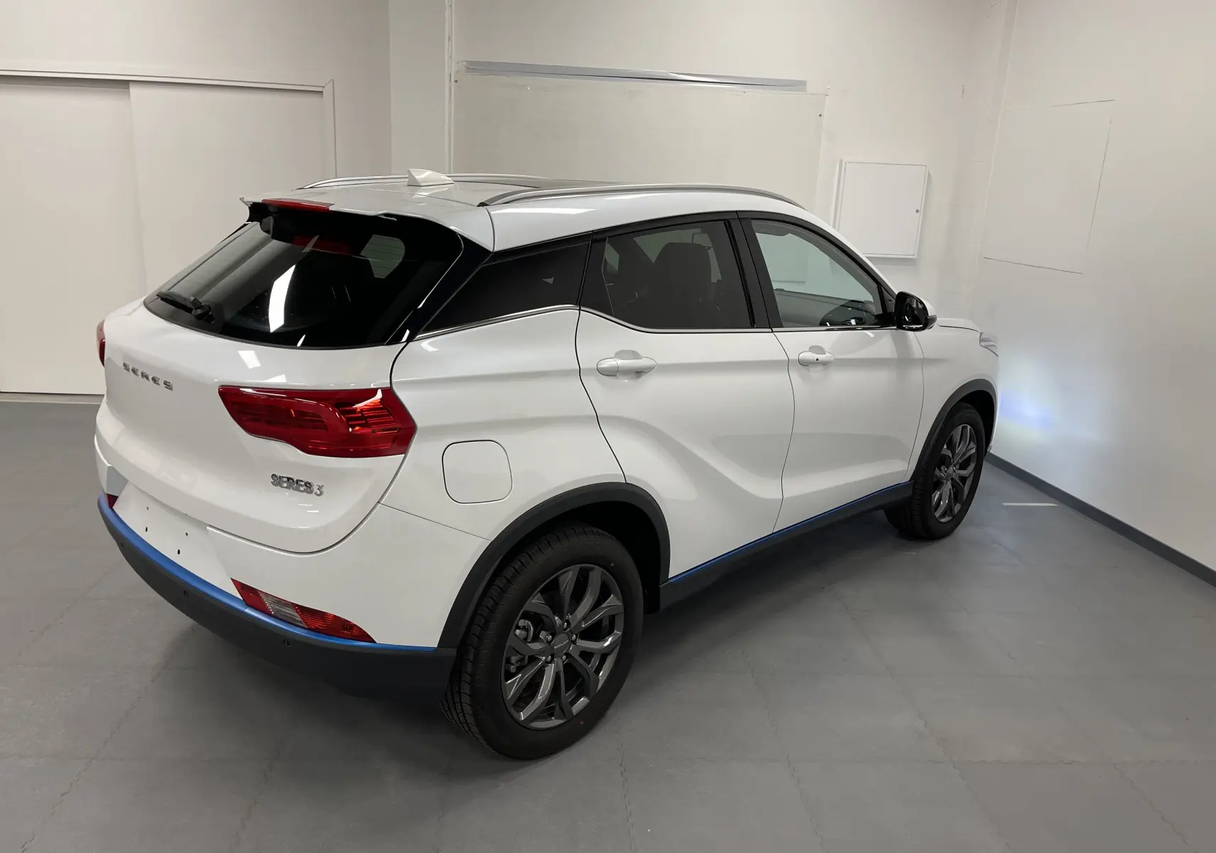 Vue 3/4 arrière droite du SUV électrique blanc SERES 3 Luxury avec jantes foncées et toit panoramique.