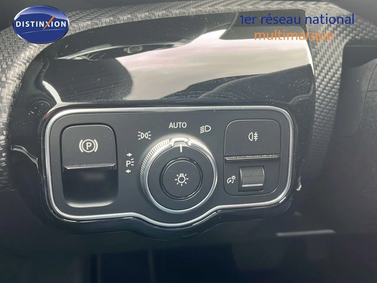 Gros plan sur le panneau de commande des phares et du frein à main électrique d'une Mercedes CLA Shooting Brake argent iridium.