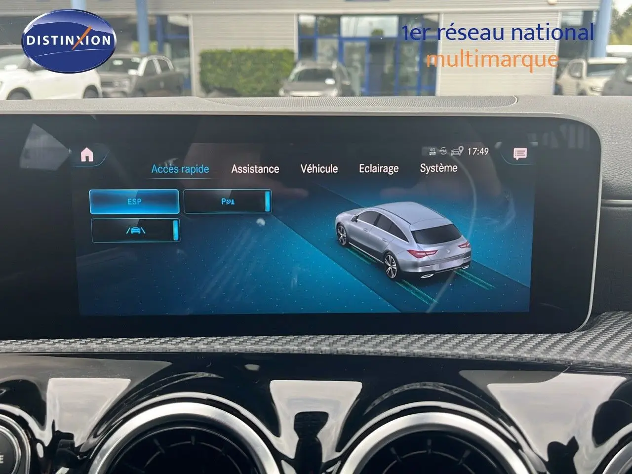 Écran multimédia montrant une Mercedes Classe CLA Shooting Brake argent iridium en vue 3/4 arrière sur interface d'assistance.