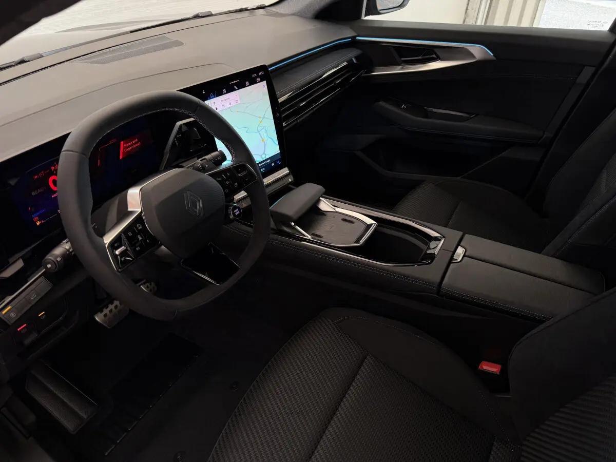 Vue intérieure côté conducteur du Renault Espace esprit Alpine 2025, tableau de bord noir avec écran tactile vertical et volant cuir suédé.