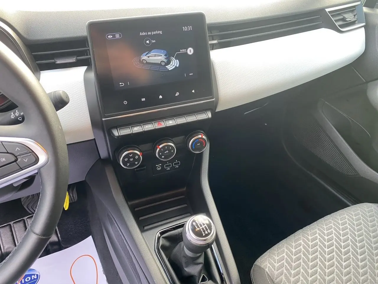 Intérieur de Renault Clio V TCE 90 Evolution, vue console centrale avec écran tactile, climatisation et levier de vitesse manuel.