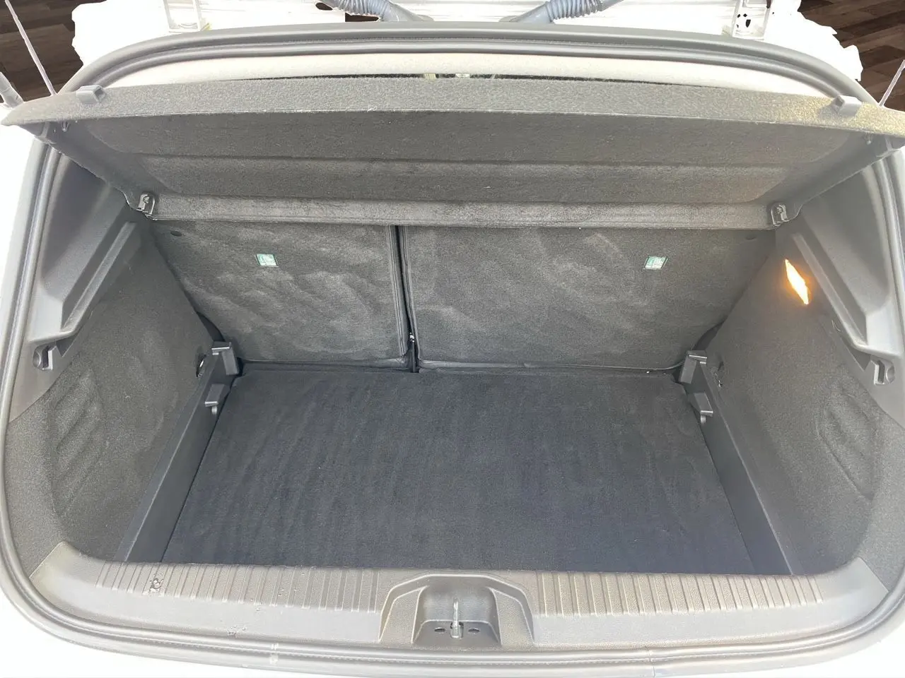 Coffre ouvert de la Renault Clio V TCE 90 Evolution gris Highland, montrant un compartimentage spacieux et tapis noir.