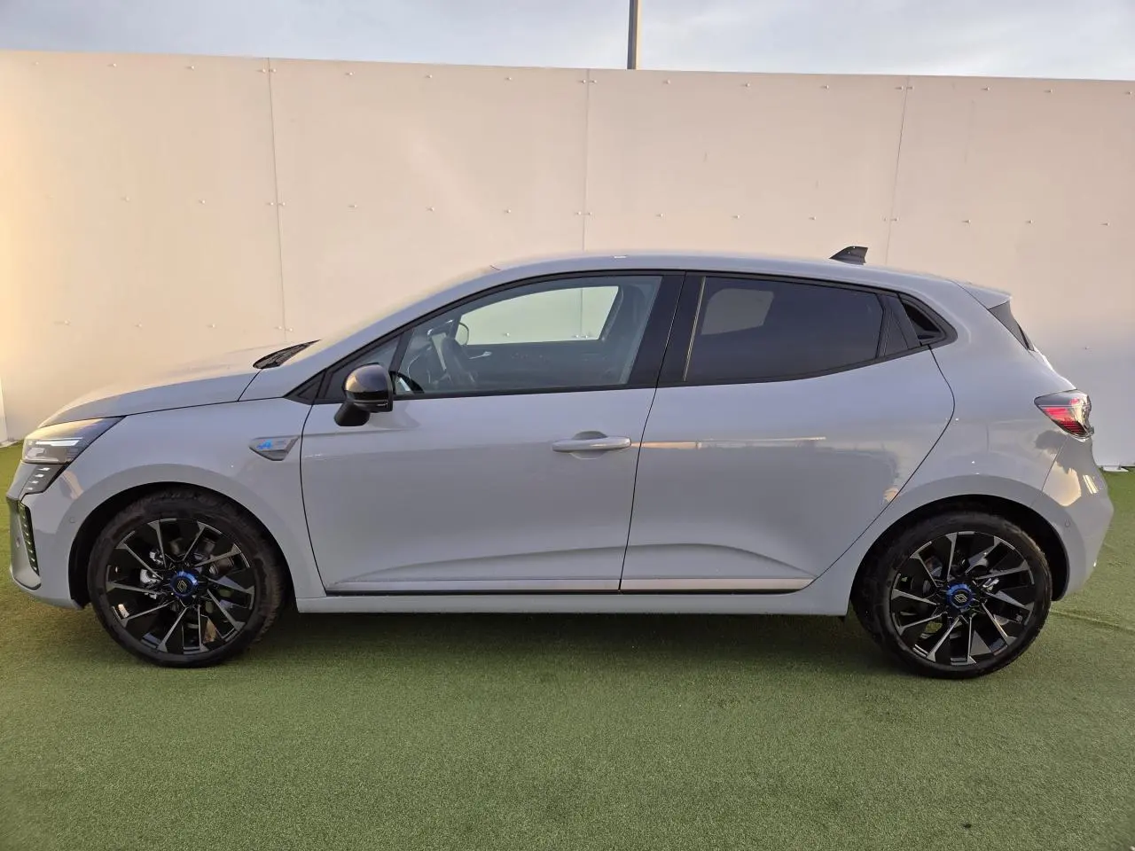 Profil droit d'une Renault Clio V hybride gris Rafale avec jantes alliage noires et vitres surteintées.
