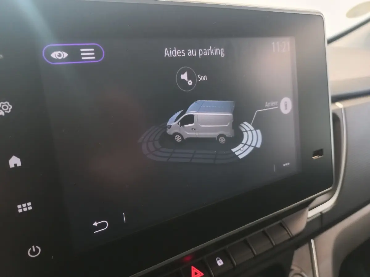 Écran tactile intérieur montrant l’aide au parking du Renault Trafic Fourgon blanc, vue de profil côté droit.