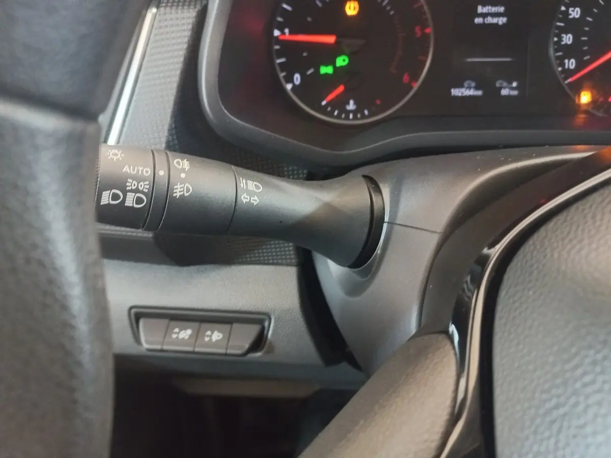 Gros plan sur la manette de commande des phares à gauche du volant dans le tableau de bord du Renault Trafic Fourgon blanc.