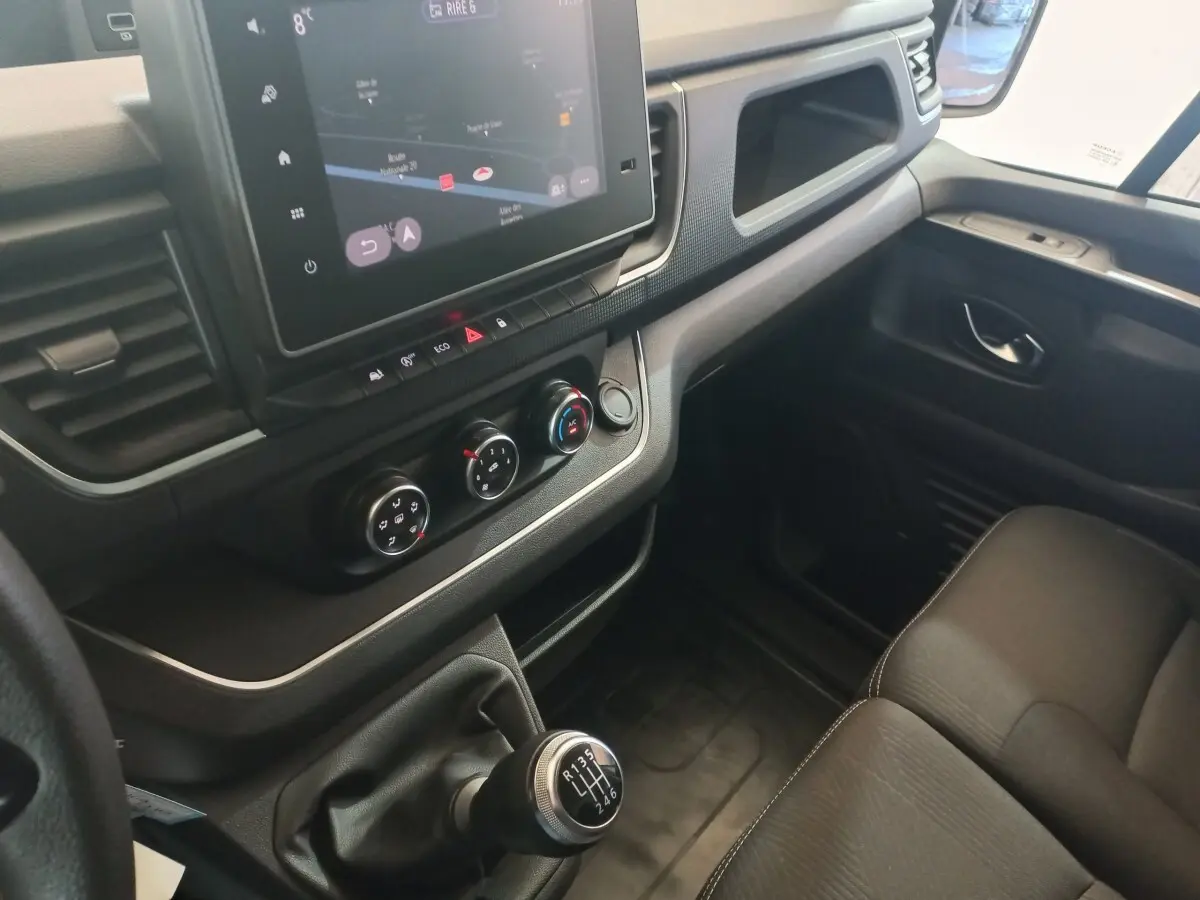 Vue intérieure côté passager du tableau de bord et levier de vitesses manuel du Renault Trafic Fourgon blanc 2022.