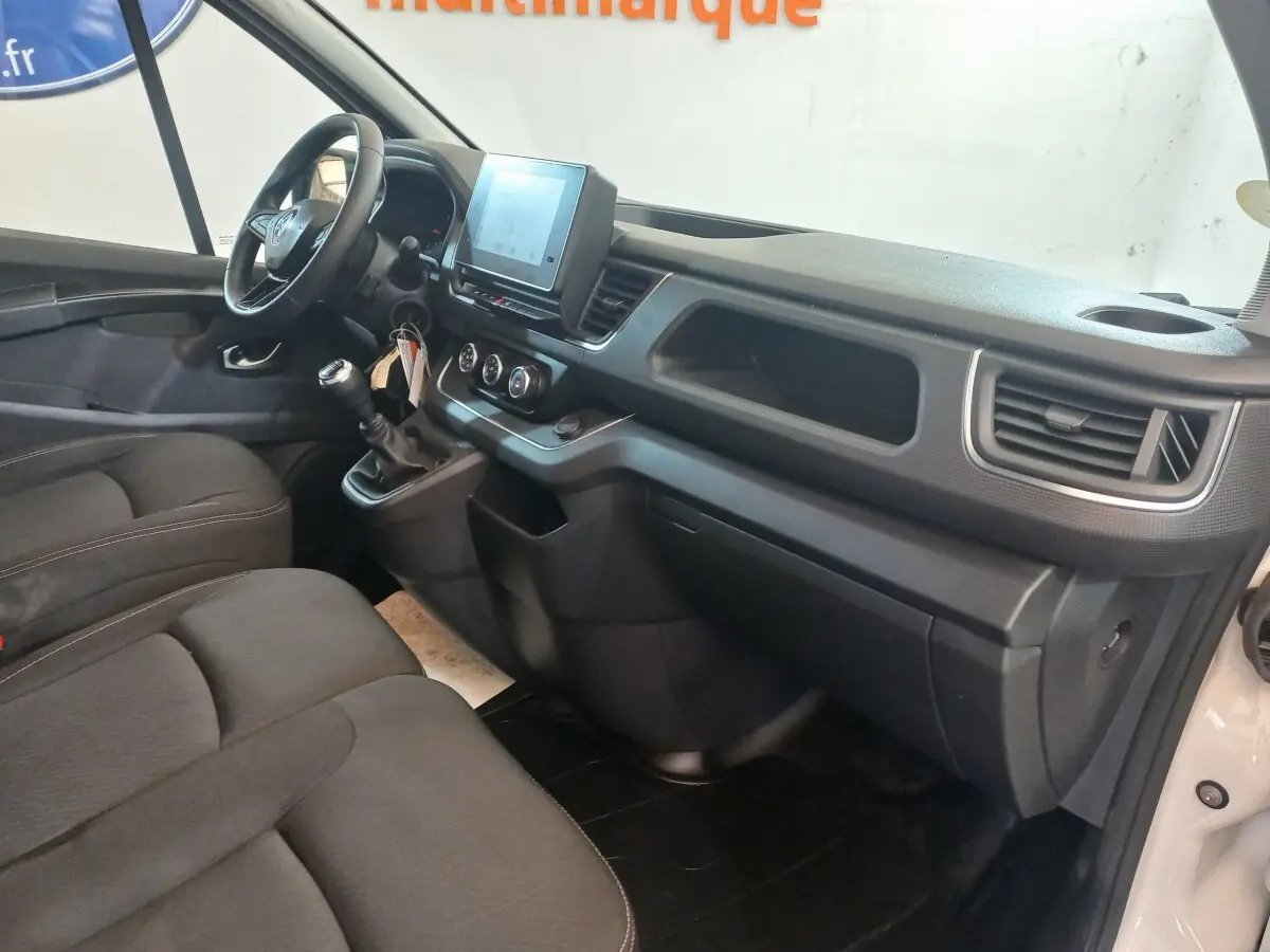 Vue intérieure côté conducteur du Renault Trafic Fourgon blanc 2022, tableau de bord avec écran tactile et volant multifonctions.