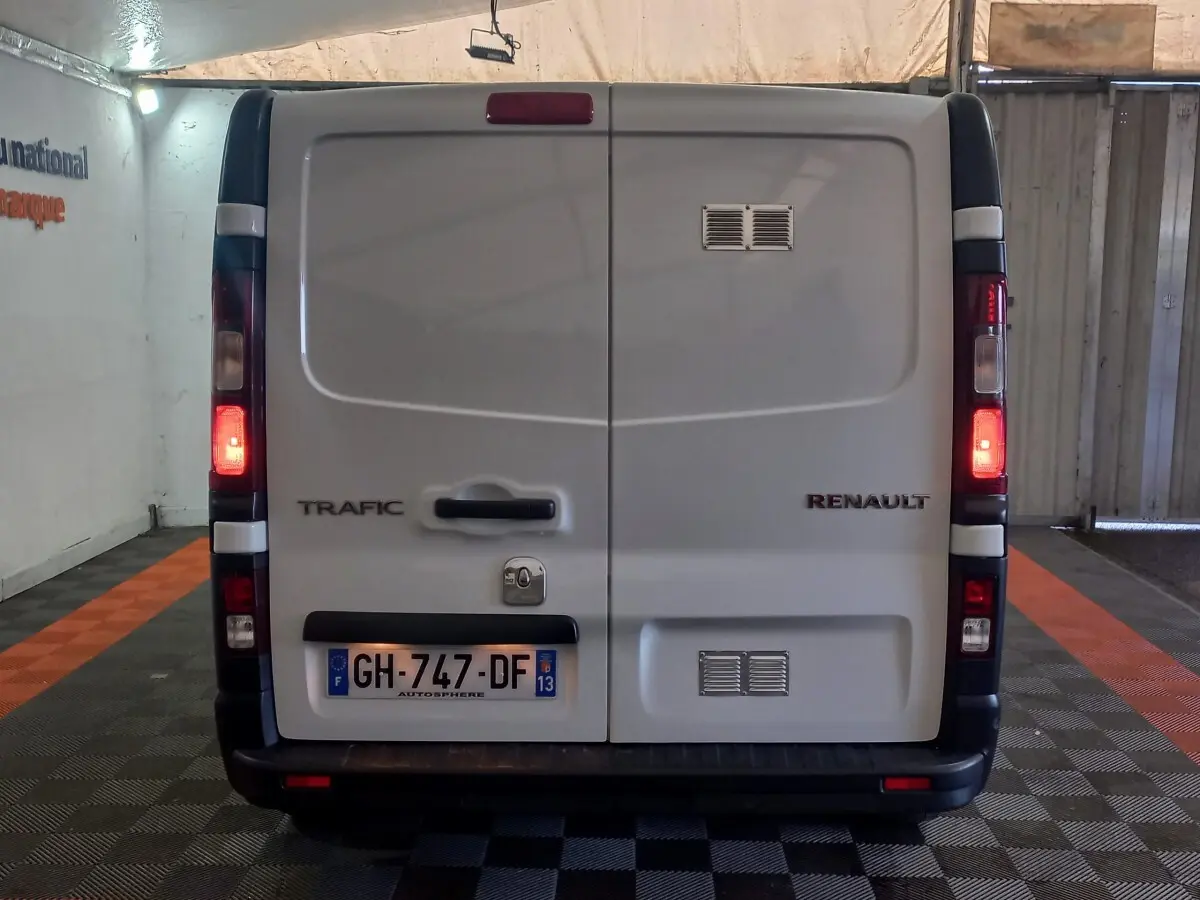 Vue arrière d’un Renault Trafic Fourgon blanc 2022 avec feux arrière allumés et plaques d’immatriculation françaises.