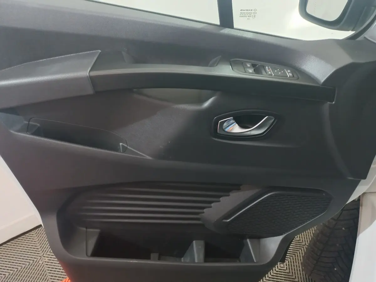 Vue rapprochée de la porte avant droite noire du Renault Trafic Fourgon avec poignée argentée et commandes électriques.