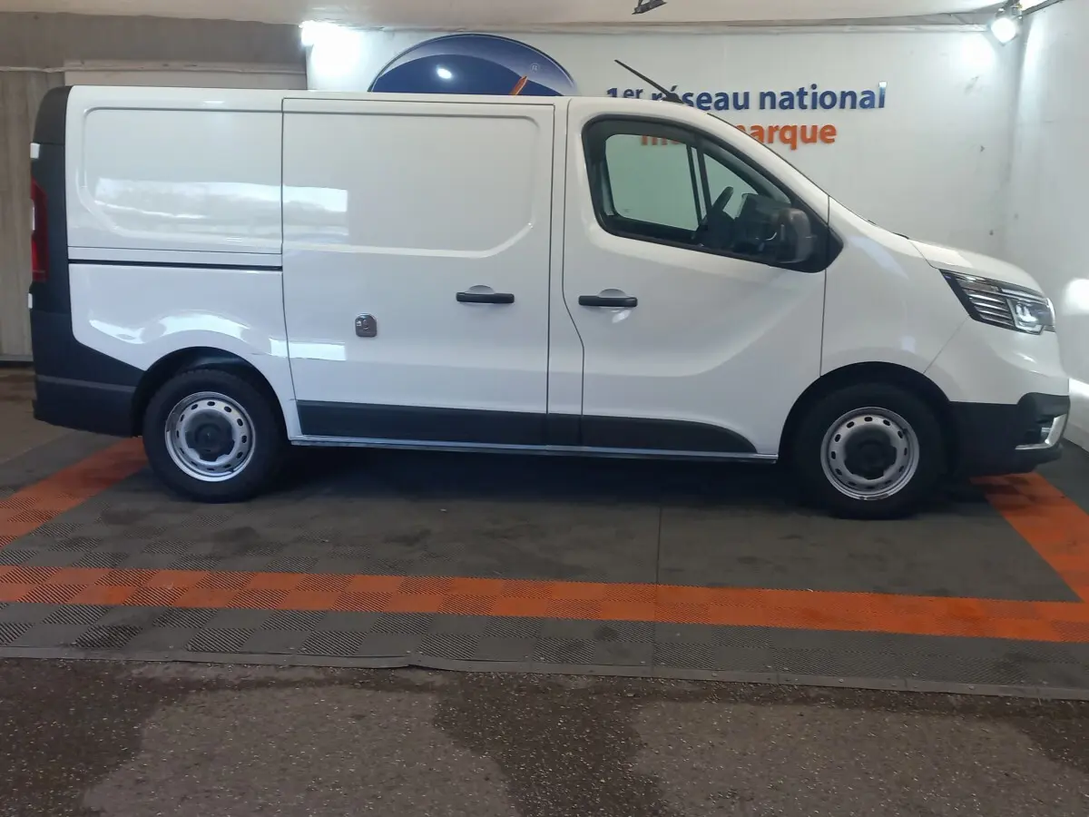 Vue de profil côté gauche d’un Renault Trafic Fourgon blanc, version utilitaire avec portes latérales pleines.