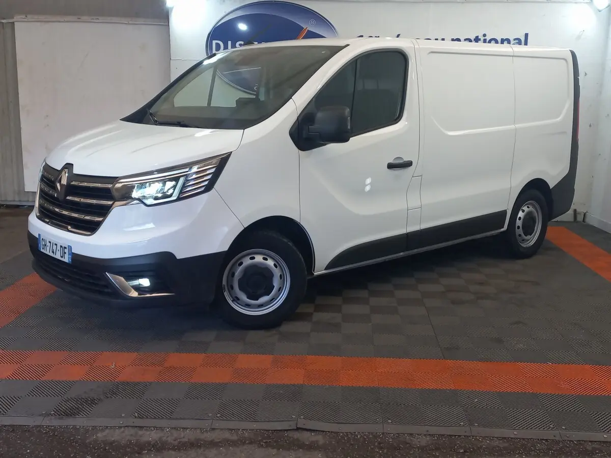 Renault Trafic Fourgon blanc vu de 3/4 avant droit, avec phares LED allumés et jantes acier grises.