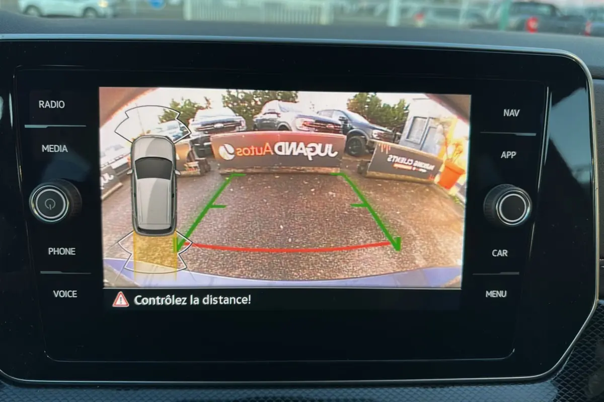 Écran de caméra de recul du Volkswagen T-Cross gris cendré, affichant les lignes de guidage et l'alerte de distance.