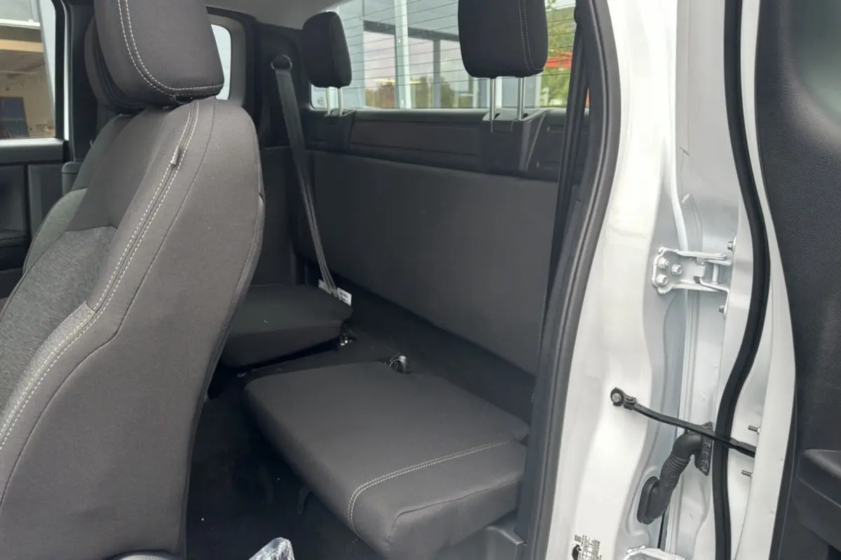 Vue intérieure côté droit du Ford Ranger blanc glacier 2025, montrant la banquette arrière rabattue et les sièges avant en tissu noir.