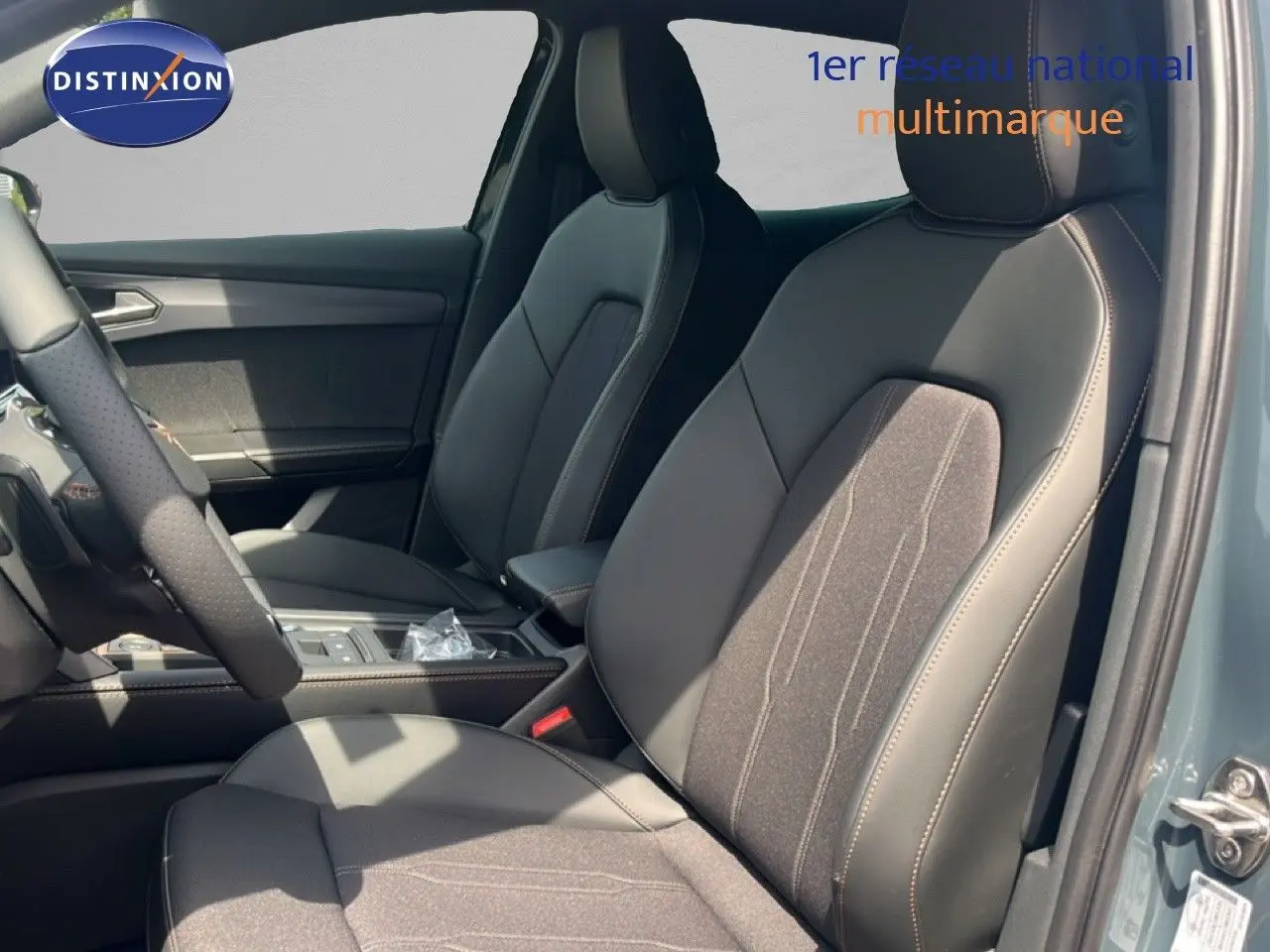 Vue intérieure côté conducteur de la CUPRA Formentor 1.5 eTSI 150CH DSG7 avec sièges en cuir et tissu noir, porte ouverte.