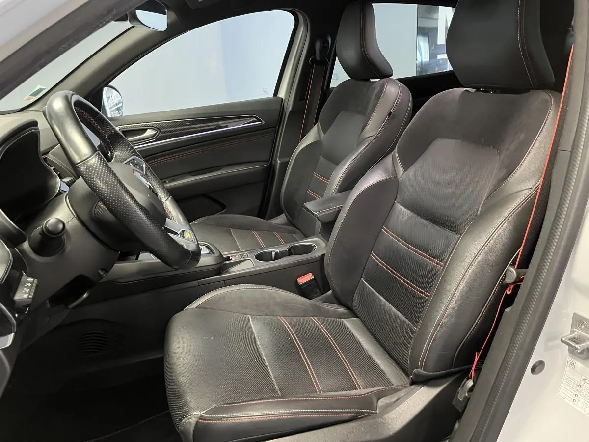 Intérieur côté conducteur du Renault Arkana blanc 2022, sièges R.S. Line cuir-suédine noirs avec surpiqûres rouges.