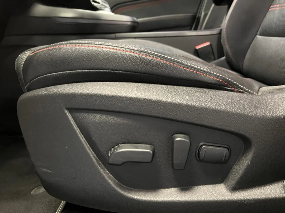 Détail des commandes de réglage électrique du siège avant droit noir avec surpiqûres rouges dans Renault Arkana R.S. Line.