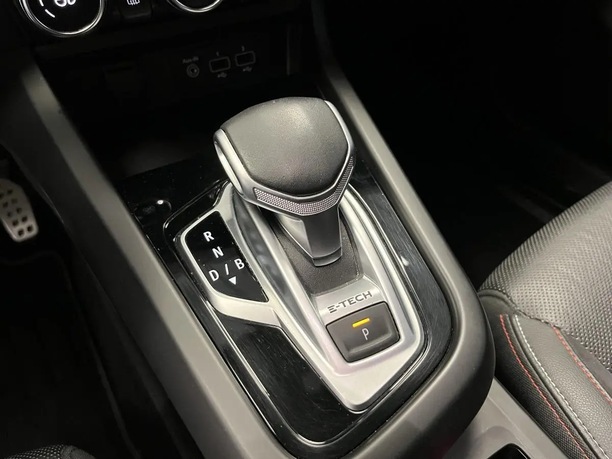 Levier de vitesse e-shifter E-Tech en gros plan dans l'habitacle du Renault Arkana blanc, surpiqûres rouges visibles sur siège cuir.