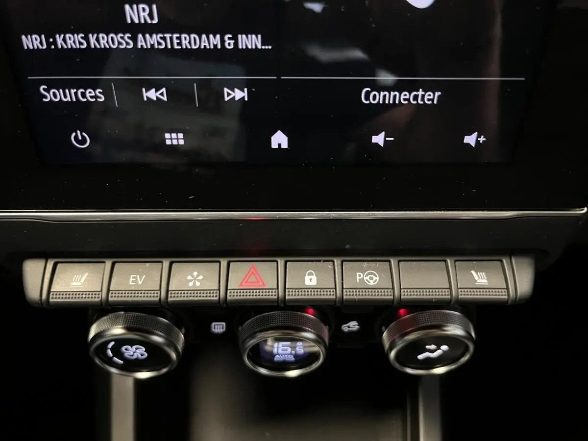 Gros plan sur la console centrale du Renault Arkana blanc, avec commandes climatisation et écran tactile visible.