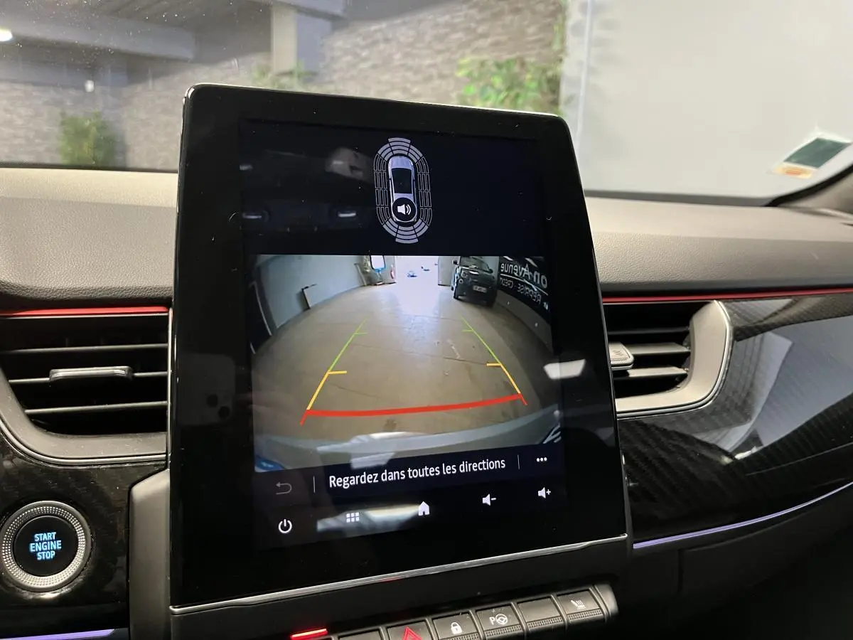 Écran tactile central affichant la caméra de recul dans l’habitacle du Renault Arkana blanc, avec détails carbone et liseré rouge.