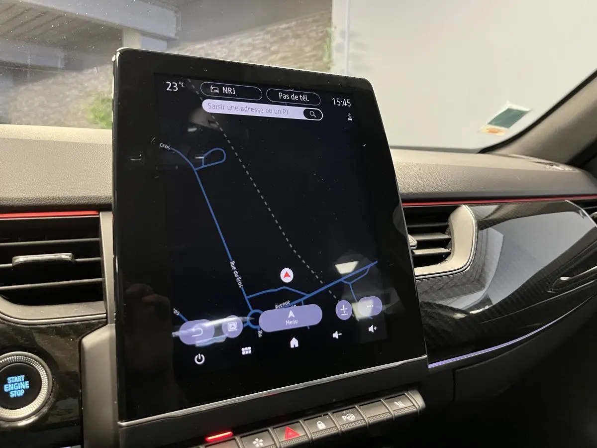 Vue rapprochée de la console centrale du Renault Arkana blanc, écran tactile Easy Link avec finition carbone et bandeau rouge.