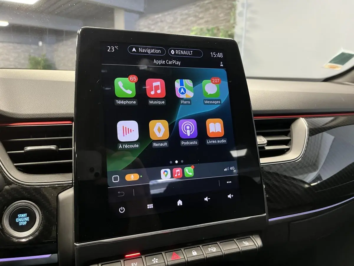 Écran tactile central affichant Apple CarPlay dans l'habitacle du Renault Arkana blanc avec finition R.S. Line.