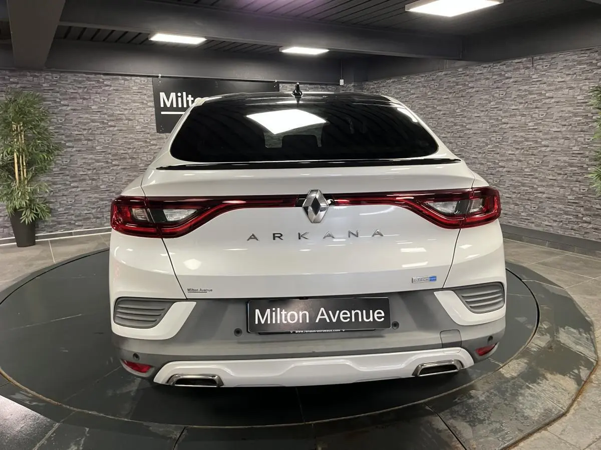 Vue arrière d'un Renault Arkana blanc perle avec toit noir brillant et double sortie d'échappement intégrée au bouclier.