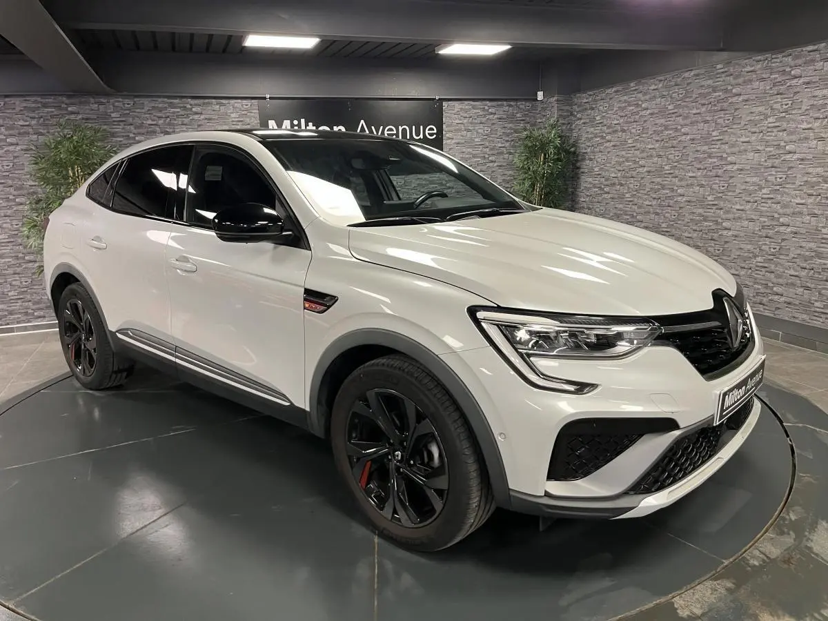 Renault Arkana 1.6 E-Tech Hybride blanc perle en 3/4 avant avec toit et rétroviseurs noirs brillants et jantes noires.